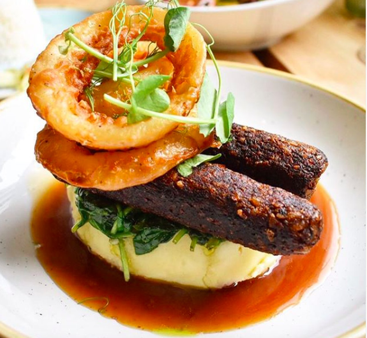 Smoked Mushroom and chestnut sausages on mushroom mash and wilted spinach, served with beer battered onion rings